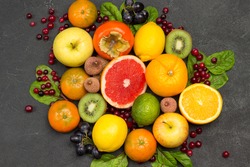 Set of varied, multicolored exotic fruits. Tangerines and oranges, kiwi and pear, persimmon and lychee. Black Background. Flat lay