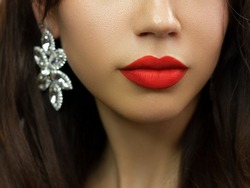 Close-up of woman's lips with fashion bright pink make-up. Beautiful female mouth, full lips with perfect makeup. Part of female face. Choice lipstick. Red wavy hair of a doll