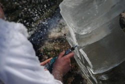 Close up of an ice carver and ice sculptor working with a block of ice.