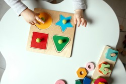 Beautiful toddler play with a wooden frame puzzle geometric figure toys at home. Toddler play with a color educational toy.  Child development.  Baby hands. View from above. Detail