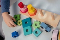 Beautiful toddler play with a wooden frame puzzle geometric figure toys at home. Toddler play with a color educational toy.  Child development.  Baby hands. View from above. Detail