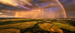 Panoramic, aerial photo of dramatic rainbow over european landscape. Large late evening rainbow over city and hills in agricultural landscape. Rainbow over Litovelske pomoravi national nature reserve.