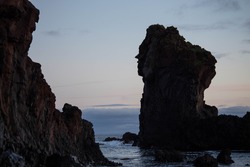 Large volcanic rock formation known as Kerling or the Troll Woman with a face shape on the side of it, at Djupalonssandur beach at sunset on the Snaefellsnes Peninsula of Iceland