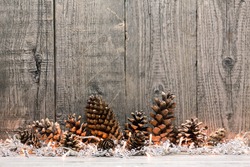 Holiday decoration with Christmas lights and cones over wooden background