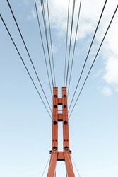Red bridge tower with thick steel cables.