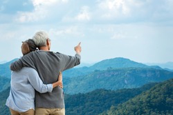 Asian Lifestyle senior couple hug and pointing the mountain nature.  Old people happy in love romantic and relax time.  Tourism family elderly retirement travel in summer leisure and destination.
