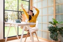 Young woman happy listen music for chill and relax after finish work.   Lifestyle girl using laptop for meeting and working  in living room at home.  Lifestyle Concept 