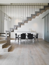 interior view of a modern dining room with dining table and iron staircase the floor isa made of wood