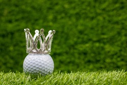 Golf ball with crown on green grass background. The 