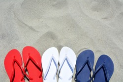 Red white and blue flip flops on the sand. Plenty of room for your text