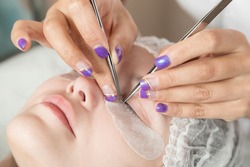 master is performing procedure of lash extension on female eyelids