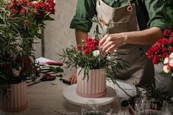 Florist make gift bouquets in hat boxes. Graceful female hands make a beautiful bouquet. Florist workplace. Small business concept. Front view. Flowers and accessories