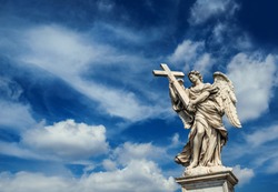 Angel holding the Holy Cross with heavenly sky and copy space. A 17th centuty baroque masterpiece at the top of Sant'Angelo Bridge in the center of Rome