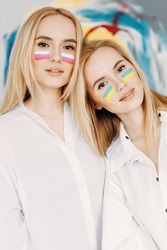 Flags are painted on the girls' faces. Twin sisters with flags of Russia and Ukraine.