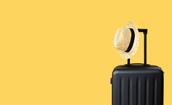 Summer holidays, vacation and travel concept. Suitcase or luggage bag with sun hat on yellow background for copy space.                                 