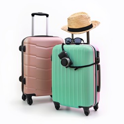Suitcase or luggage bag with sun glasses, camera and hat on pastel green background. Summer holidays, vacation and travel concept. 