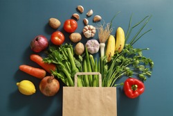 Paper bag of different tropical fresh fruits and vegetables. Healthy eating and grocery shopping concept. Top view. Flat lay