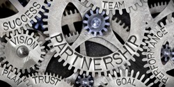 Macro photo of tooth wheel mechanism with Partnership related words imprinted on metal surface
