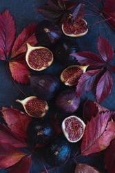 Ripe figs with red grape leaves. Autumn still life. Dark background 