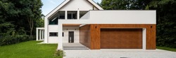 Panorama of elegant white house with wood decor on garage and green lawn