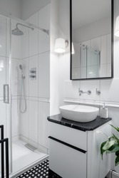 Elegant and small bathroom with shower and stylish washbasin with black and white cabinet with drawer