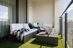 Nice balcony with rattan corner sofa and coffee table and synthetic grass on the floor