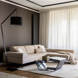 Fancy living room with stylish, beige, corner sofa, beige carpet, modern, black coffee table, simple black lamp and big windows behind curtains