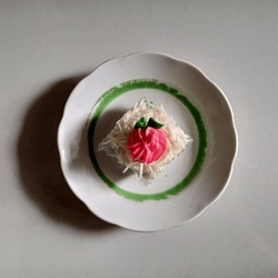 pandan cake sprinkled with grated cheese with cream decoration in the shape of a single pink and green flower