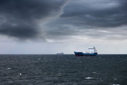 Dark cloudy stormy sky with ship and waves in the sea.