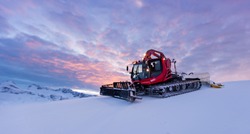 Snowplow machine at snowy ski resort during sunset