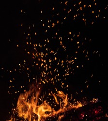 Burning sparks flying. Beautiful flames. Fiery orange glowing flying away particles on black background.