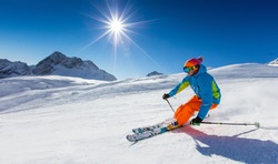 Skier skiing downhill during sunny day in high mountains