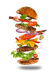 Big tasty home made burger with flying ingredients on white background.