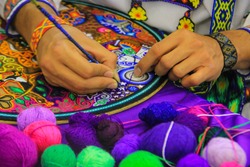Close up of a Mexican man working of his handcraft with bokeh of yarn in front.