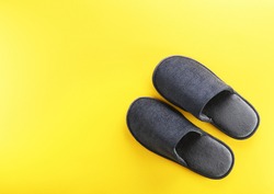 Gray home slippers on a yellow paper background. View from above. Copy space