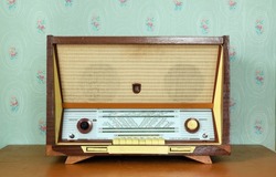 Vintage radiogram (radio) on the background of old wallpaper. Latvian Soviet vintage radiola (radio) was produced from 1965 to 1968.