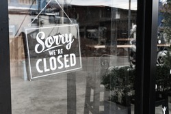 Sorry we're closed sign. grunge image hanging on a dirty glass door.