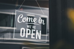 Come in we're open, vintage black retro sign in glass door storefront