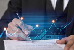 Businessman in suit signs contract. Double exposure with financial chart hologram. Man signing mortgage agreement. Real estate market analysis and investment concept.