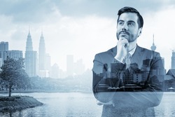 Young handsome businessman in suit with hand on chin thinking how to succeed, new career opportunities, MBA. Kuala Lumpur on background. Double exposure.