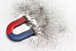 Red and blue horseshoe magnet or physics magnetic with iron powder magnetic field on white background. Scientific experiment in science class in school.