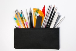 Student pencil bag or pencil case with school supplies for student. Black pencil box with school equipment isolated on white background. Top view