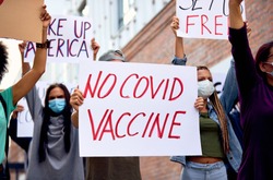 Anti-vaccine activists wearing protective face mask while protesting against coronavirus vaccination on city streets. 