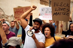 Displeased black couple shouting while marching with group of people on  anti-racism protest.