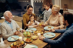 Cheerful extended family communicating while gathering around dining table at home. 