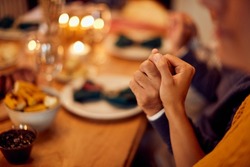 Close-up of Jewish couple saying grace at dining table during Hanukkah.