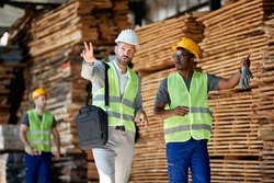 Warehouse manager talking to African American worker while walking through  lumber distribution department..
