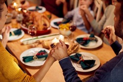 Close-up of multigeneration family blessing the food while saying grace during Thanksgiving dinner at dining table.