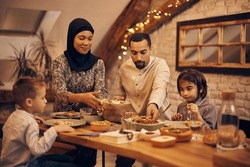 Muslim family gathering around dining table for Ramadan dinner. 