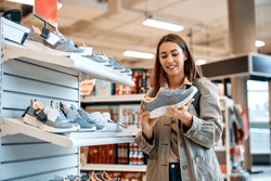Young happy woman buying sports shoes at shopping mall. 